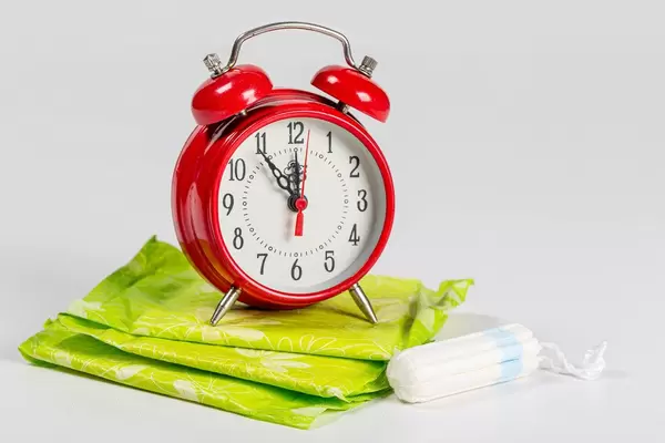 Alarm clock, pads and tampon on a white background. Concept of menstrual cycle, personal hygiene items