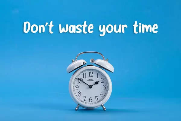 Alarm clock with Don't waste your time text on blue background