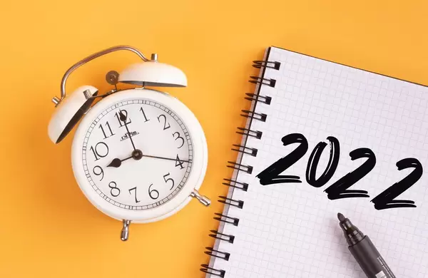 Alarm clock with handwritten 2022 text on yellow background