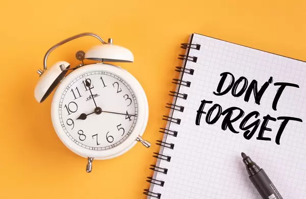 Alarm clock with handwritten Don't Forget text on yellow background