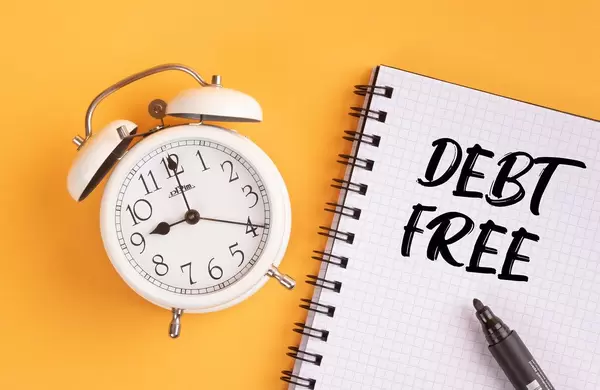 Alarm clock with handwritten text Debt Free on yellow background
