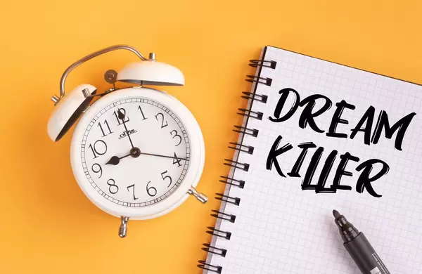 Alarm clock with handwritten text Dream Killer on yellow background