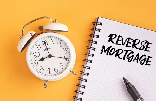 Alarm clock with handwritten text Reverse Mortgage on yellow background