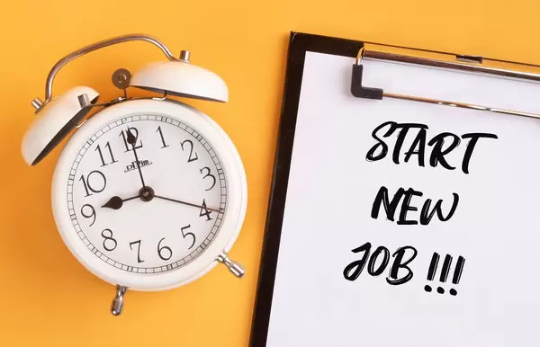 Alarm clock with handwritten text Start New Job on clipboard