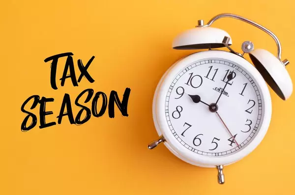 Alarm clock with handwritten text Tax Season on yellow background