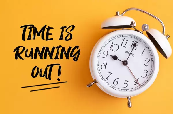 Alarm clock with handwritten text Time is Running Out on yellow background