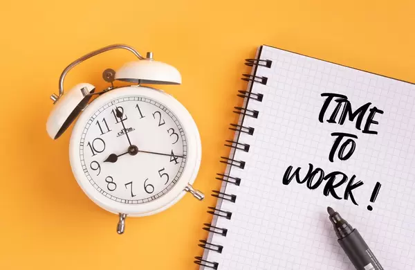 Alarm clock with handwritten Time to Work text on yellow background