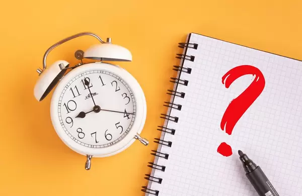 Alarm clock with red question mark on yellow background