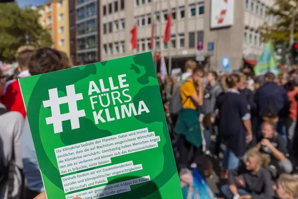 #AllefürsKlima Plakat mit den Klimademonstranten im Hintergrund