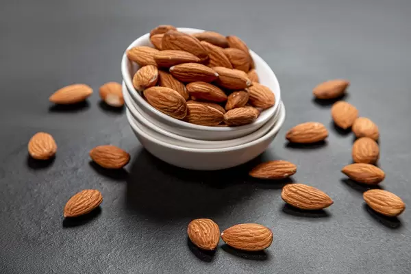 Almonds in white ceramic bowl on black background (Flip 2019)
