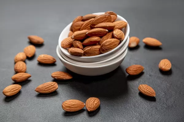 Almonds in white ceramic bowl on black background