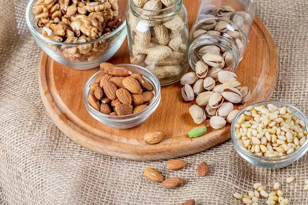 Almonds, pistachios, pine nuts and walnuts on a wooden kitchen board with burlap (Flip 2020)