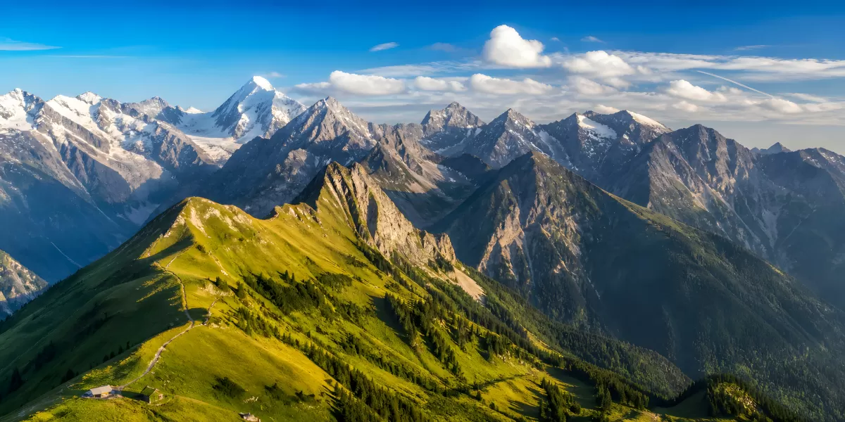 Alpenpanorama mit grünen Hängen und Gipfeln im Sommer