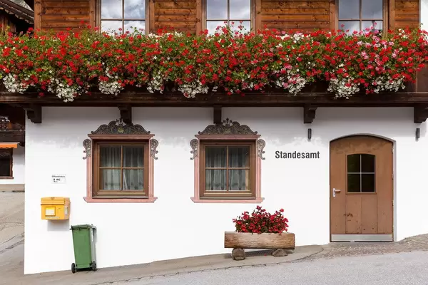 Alpine architecture: wooden door and windows, balcony with many flowers. Alpbach registry office
