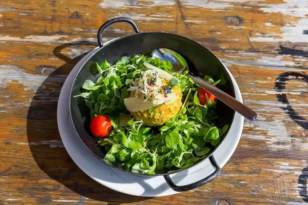 Alpine food in Tyrol, Austria: a pumpkin Knödel served in a pan with green salad and tomatoes