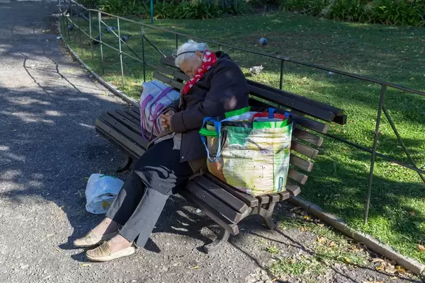 Alte Frau schläft auf einer Parkbank