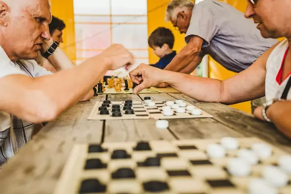 Alte Männer spielen Schach und andere Brettspiele gegeneinander