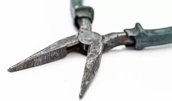 Alte Spitzzange mit Rostflecken, auf weißem Untergrund