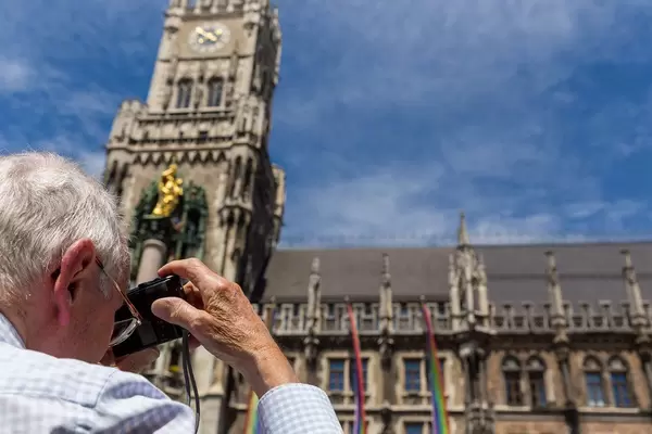 Alter Mann fotografiert bunte Regenbogenfahnen vor dem Neuen Rathaus während des Christoper Street Day Festivalwochenendes in München