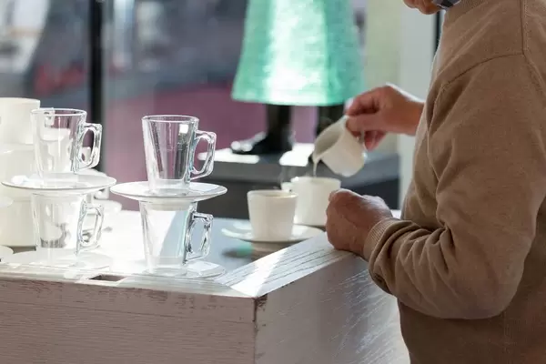 Älterer Herr gießt Milch in seinen Kaffee