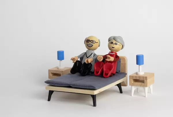 Älteres Paar liegt freudig in hölzernen Miniatur-Puppenbett - Makroaufnahme zentral