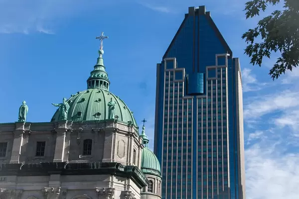 Altes, historisches Gebäude neben einem modernen Wolkenkratzer vor blauem Himmel