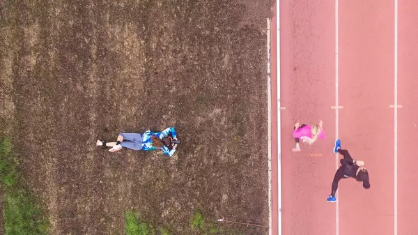 Am Bauch liegende Fotografin fotografiert Läuferinnen