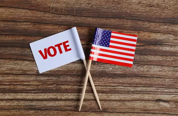 American flag and white flag with vote text on wooden table