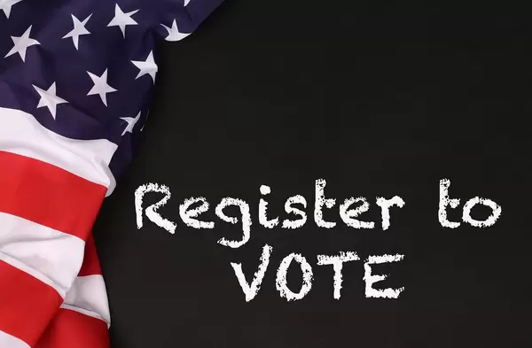 American flag with the text Register to Vote against a blackboard background