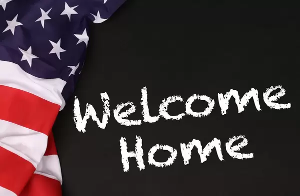 American flag with the text Welcome Home against a blackboard background