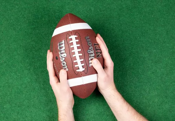 American football player holding up football ball