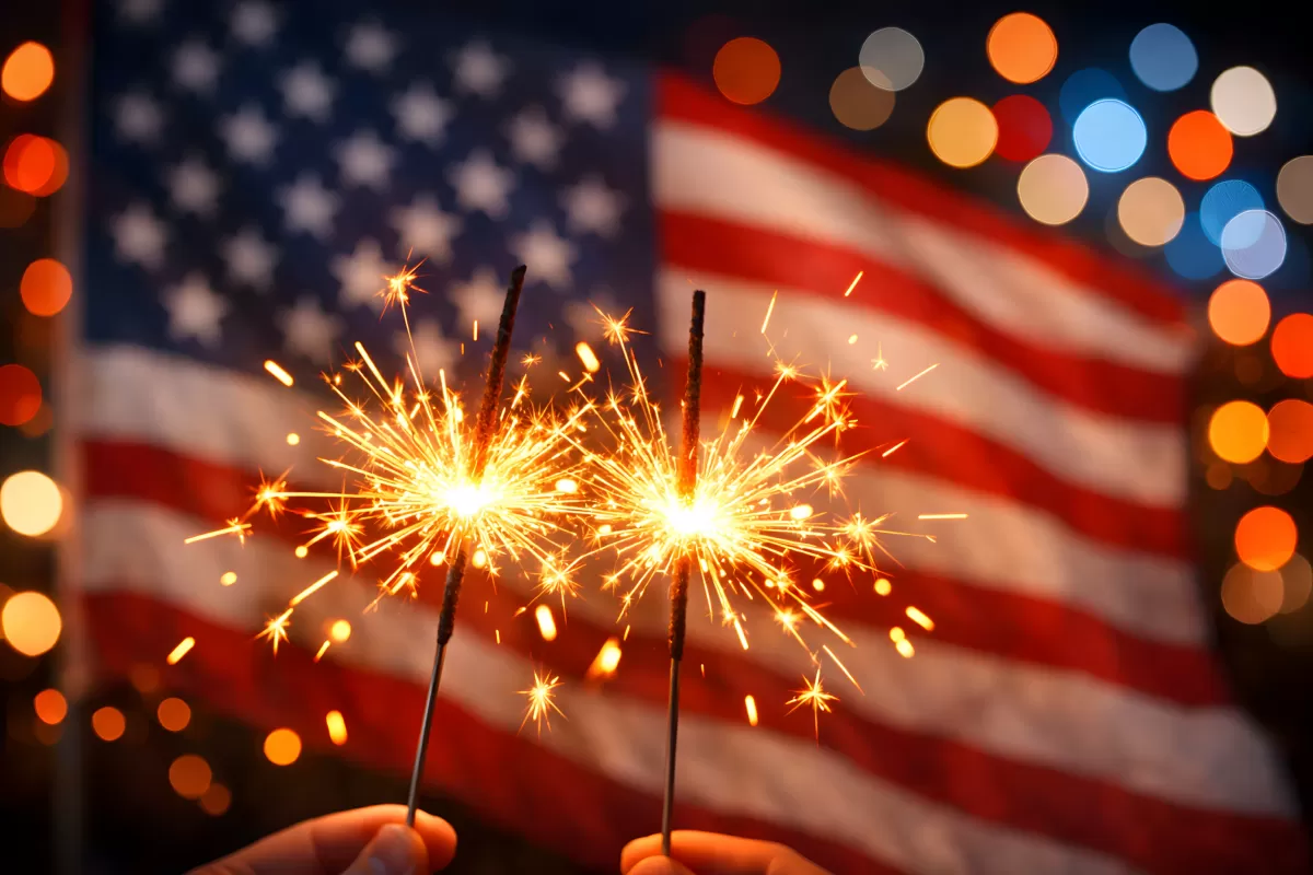 Amerikanische Flagge und Wunderkerzen vor Feiertagsbeleuchtung