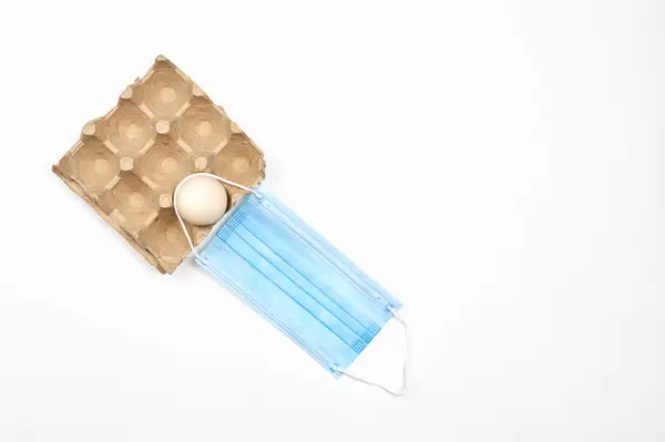 An egg with medical face mask on white