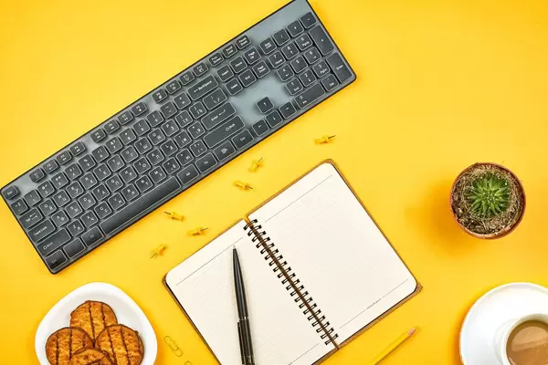 An open notebook, coffee mug and cookies on work desk