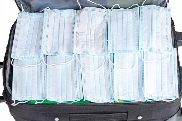 An open suitcase and many medical masks inside. Travel or business trip concept during quarantine