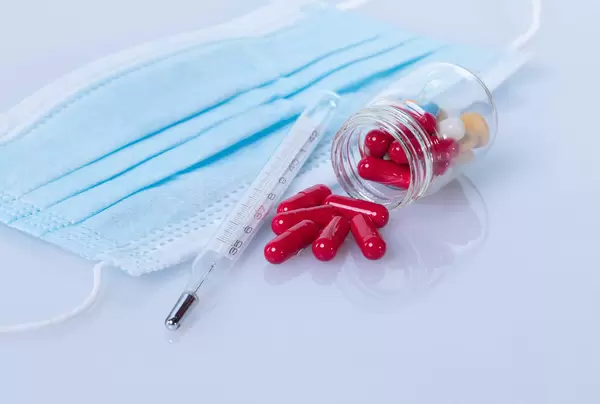 Analog thermometer with medical face mask and red pills