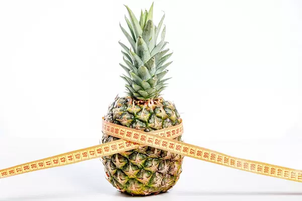 Ananas mit einem Bandmaß als Symbol von Gewichtsverlust