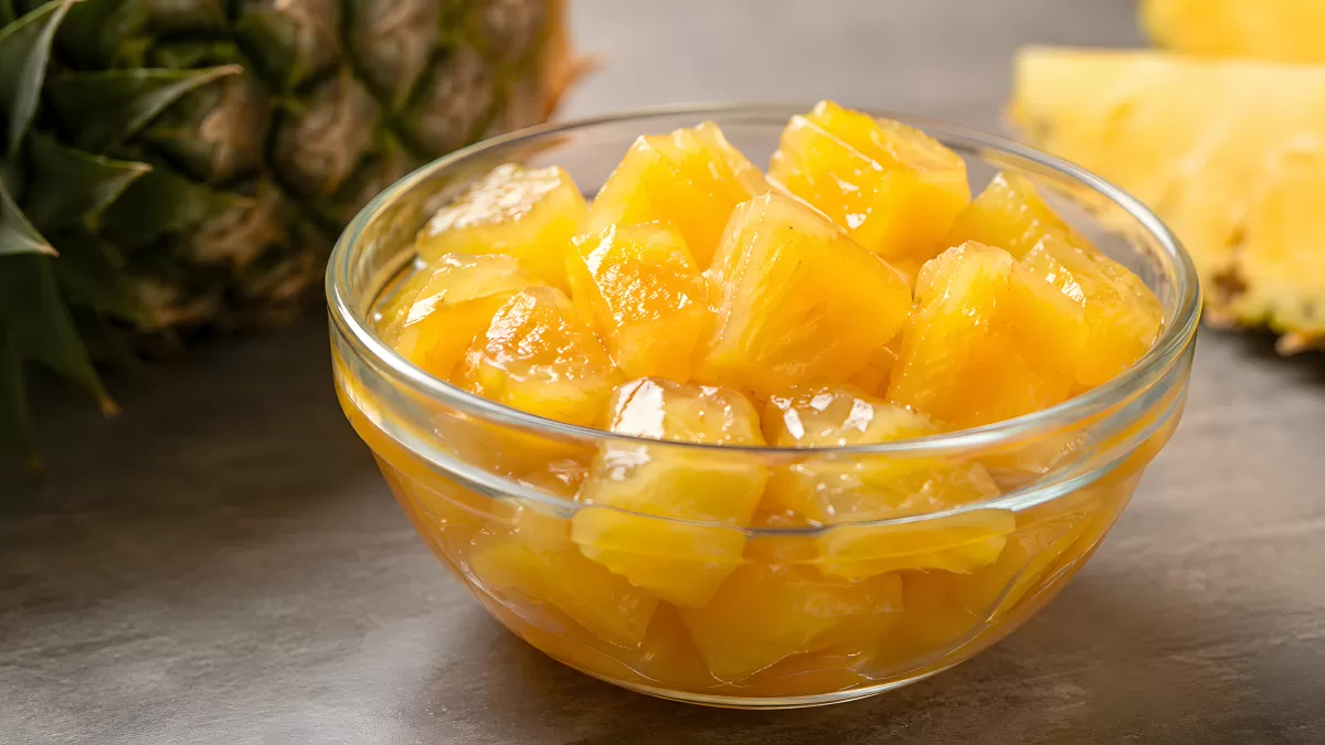 Ananasstücke in Glasschüssel mit frischer Ananas