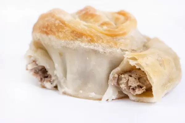 Angebissener Burek (auch Börek) mit Fleischfüllung isoliert vor weißem Hintergrund