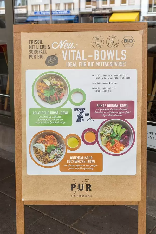 Angebotstafel vor einem deutschen Restaurant der Bio-Manufaktur PUR, mit veganen Vital-Bowls-Gerichten