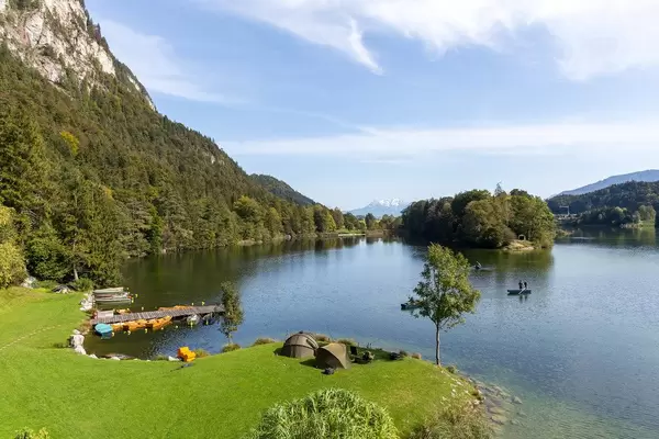 Angeln am Reintalersee in Tirol: Zelte und Campingstühle am Ufer, Angler auf Holzbooten