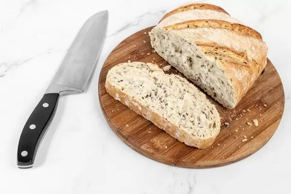 Angeschnittenes, rustikales Brot und Brotscheibe auf einem Holzbrettchen