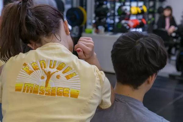 Angestellte von Renuova Massage aus Arizona, USA massiert Besucher der Fibo Gesundheitsmesse in Köln