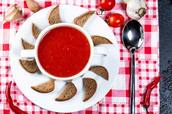 Ansicht von oben auf eine Tomatensuppe als kleine Vorspeise, mit Gewürzen und Brotkräckern