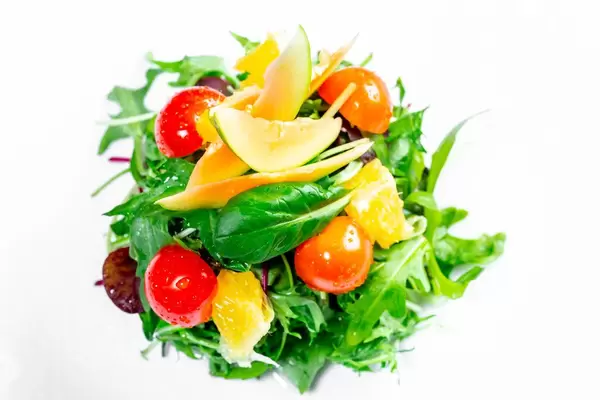 Ansicht von oben auf einen Salat-Turm mit grünen Blättern, Kirschtomaten und Avocadoscheiben