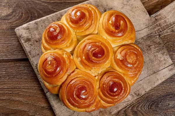 Ansicht von oben auf Gebäckrollen / Schnecken, mit Knoblauch, auf einem alten Holzbrettchen