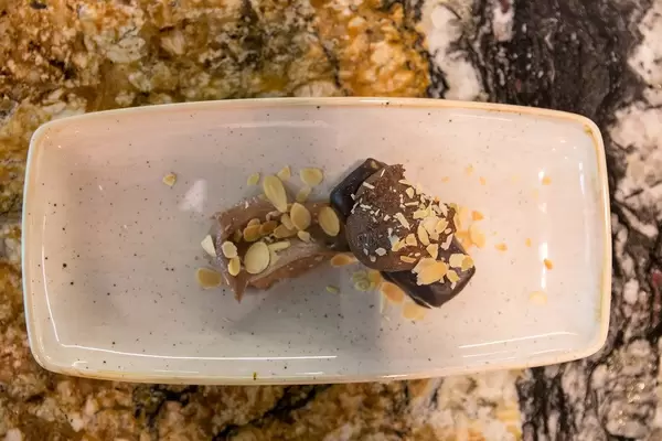 Ansicht von oben des Kokos-Schoko-Desserts mit Mandelflocken auf einem weißen Teller im Fit Kitchen Restaurant in Barcelona, Spanien