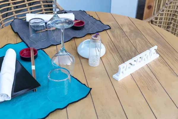 Ansprechend gedeckter, reservierter Tisch mit Essstäbchen und weißem Holzsteller „RESERVE“