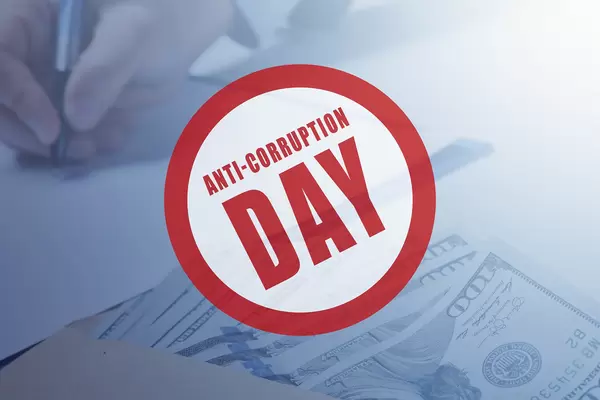 'Anti-corruption day' badge over photo of money and hand signing contract