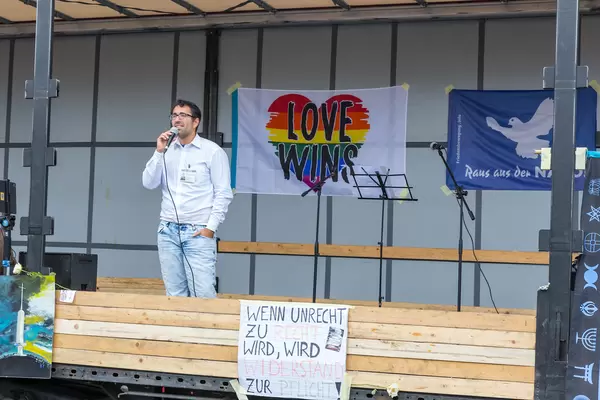 Anti-Covid protestor without face mask holds speech from truck with rainbow heart and motto "love wins"